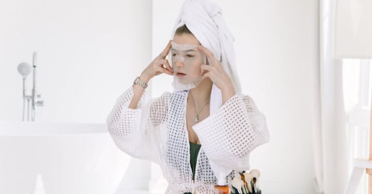 Woman applying a face mask in a bathroom, focusing on skincare and relaxation.