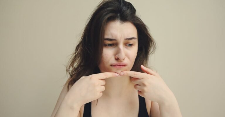 A woman looks at her skin with concern, touching her chin, worried about acne.